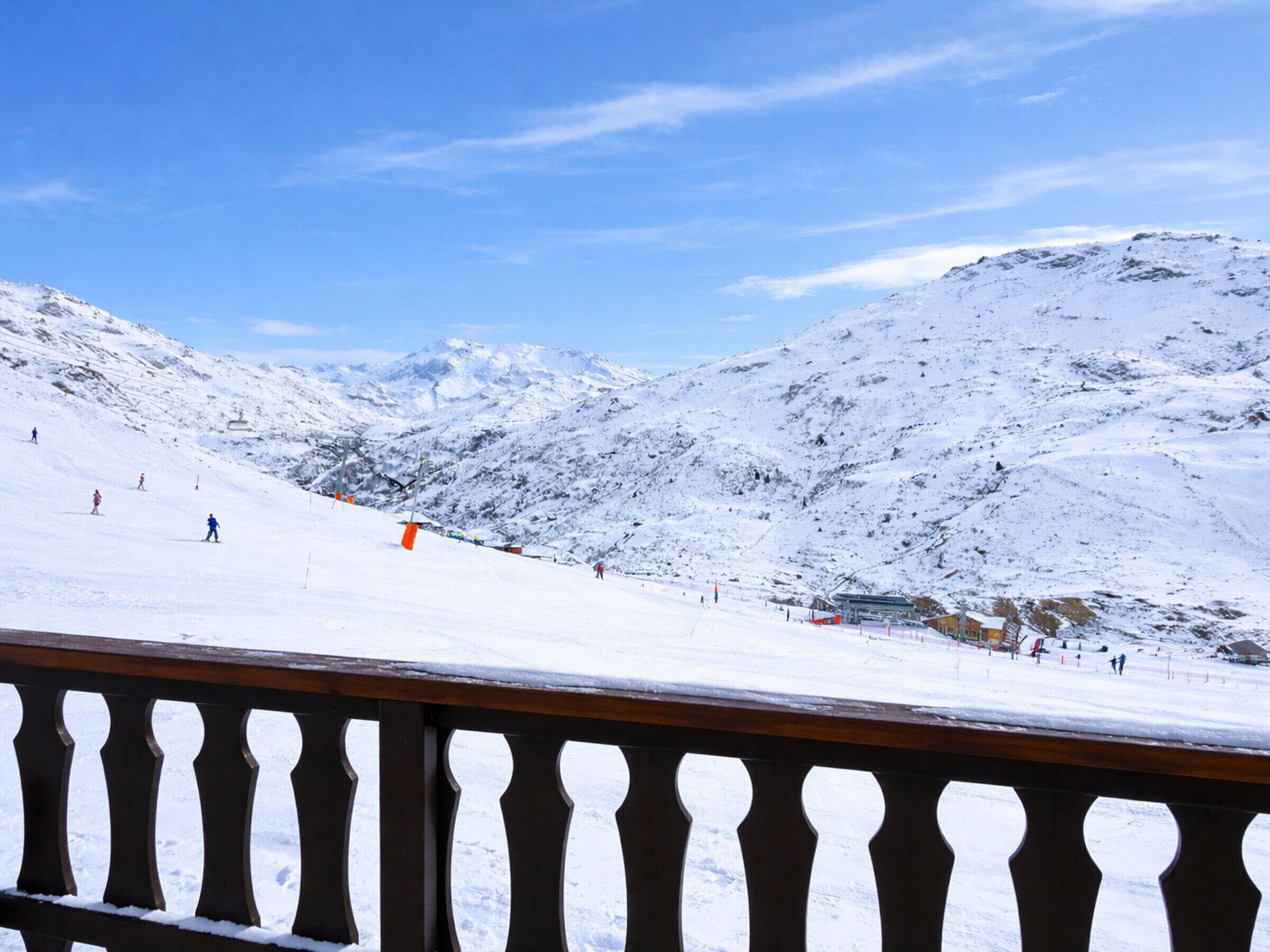 A snowy mountain landscape with a wooden fence in the foreground.