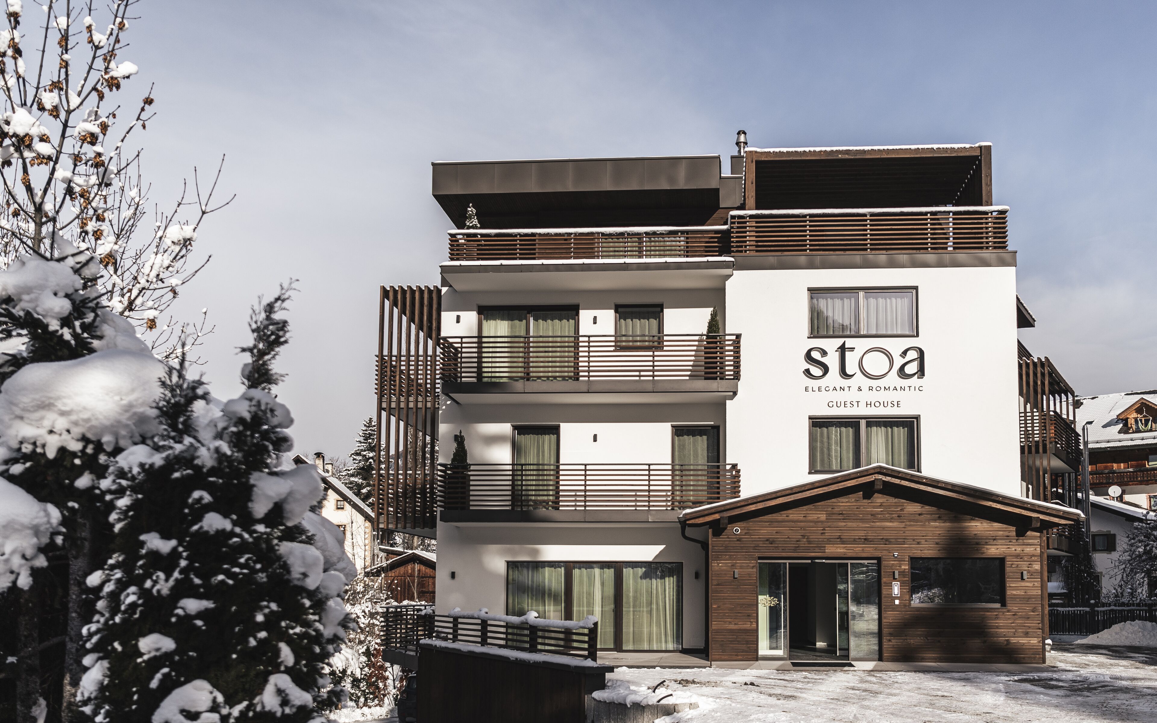 Un edificio a più piani con un'insegna che riporta “stoa” e “PENSIONI ELEGANTE & ROMANTICA”.