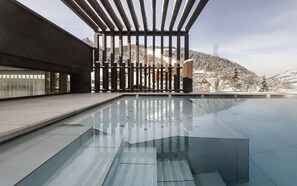 Un área de piscina moderna con vistas despejadas a un paisaje nevado y una montaña al fondo.