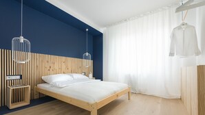 Un dormitorio moderno con una cama de madera, una mesita de noche, una lámpara colgante y un ventanal con cortinas.