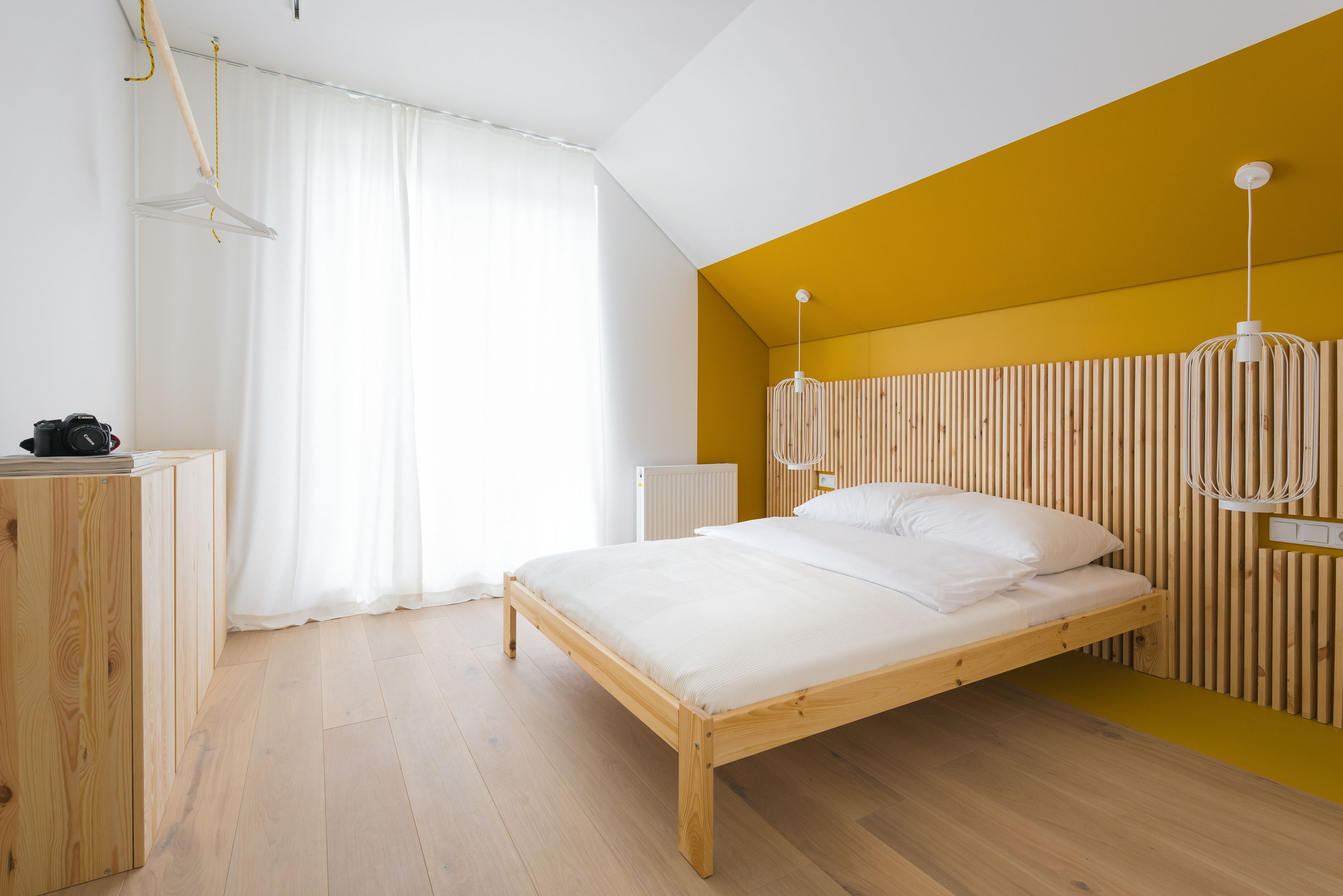 Un dormitorio con cama de madera, radiador blanco y armario de madera.