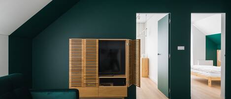 Une chambre moderne avec un plafond en pente, une armoire en bois, un lit et un mur vert.