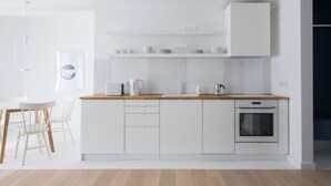 Una cocina moderna con armarios blancos, una encimera de madera y un horno empotrado.