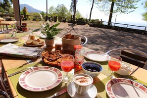 Ein Frühstückstisch mit Waffeln, einer Pflanze, einer Zeitung und Blick auf die Berge.