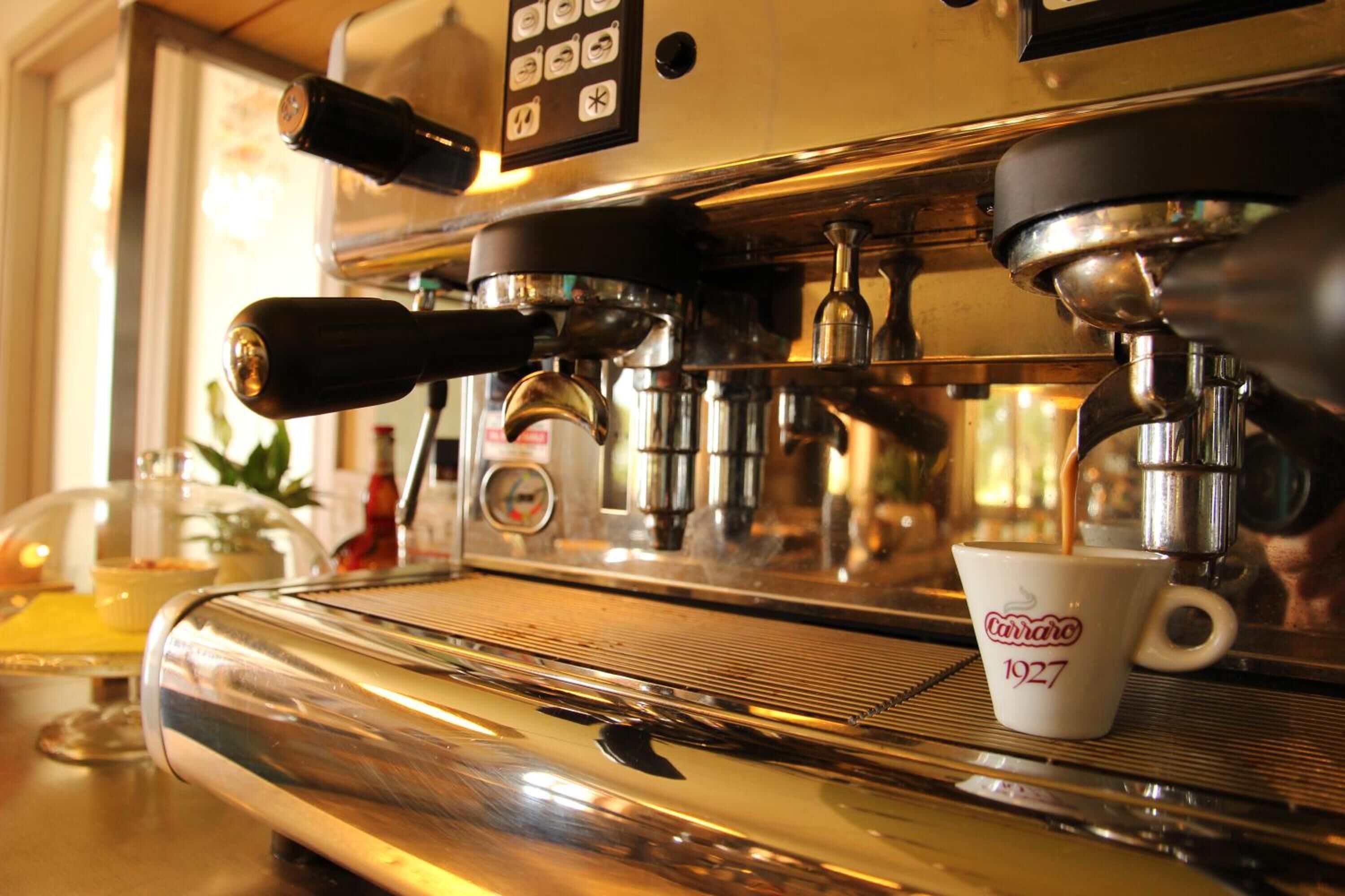 A coffee machine with a cup of coffee, a control panel, and a window in the background.