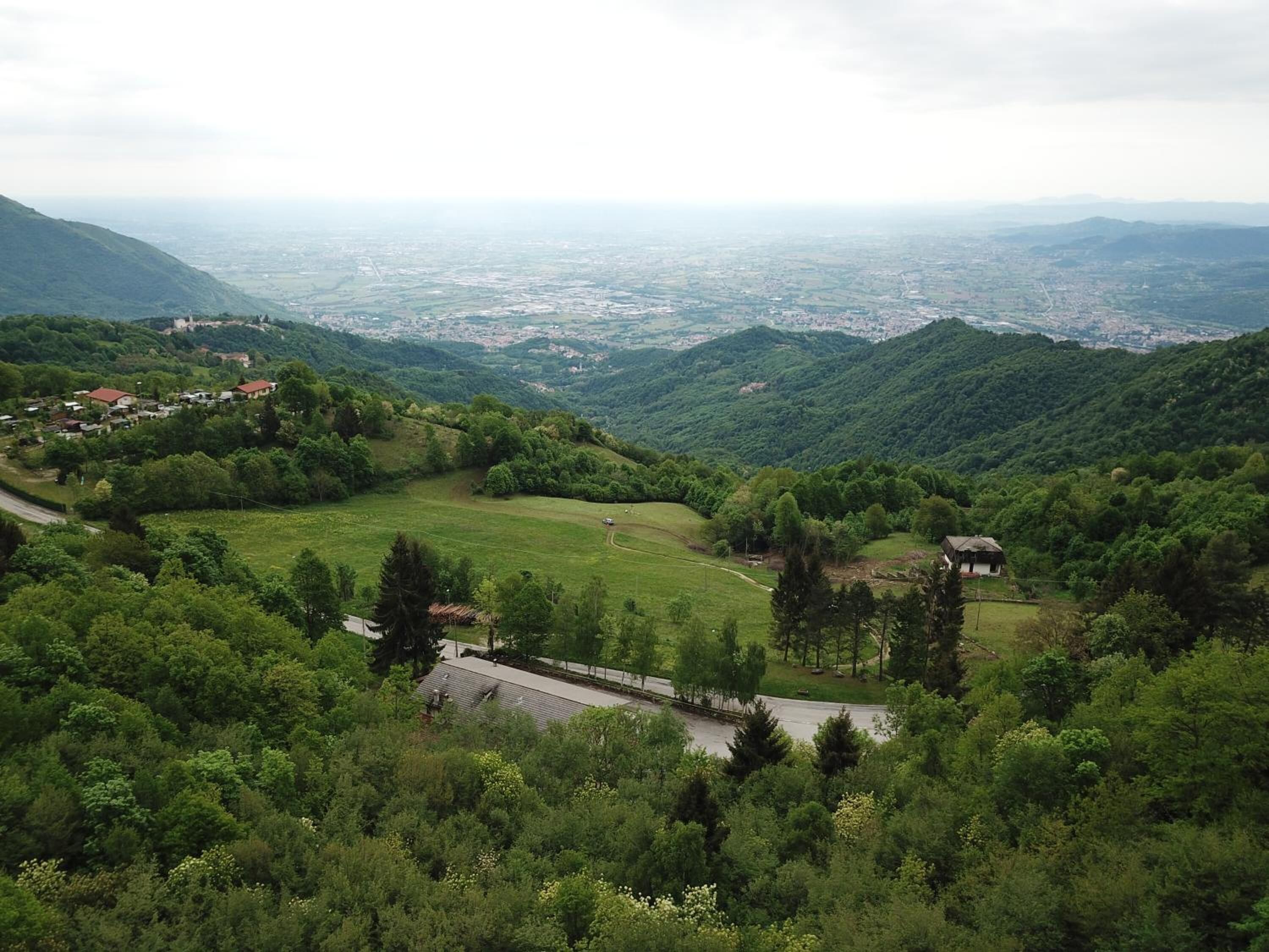 A mountainous landscape with a small village, a road, and a building with a sloped roof.