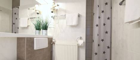 A modern bathroom with a white sink, toilet, and shower area.