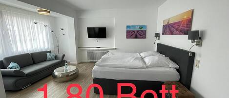 Una habitación de hotel moderna con cama, sofá, televisión y obras de arte.