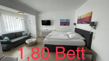 Una habitación de hotel moderna con cama, sofá y televisión.