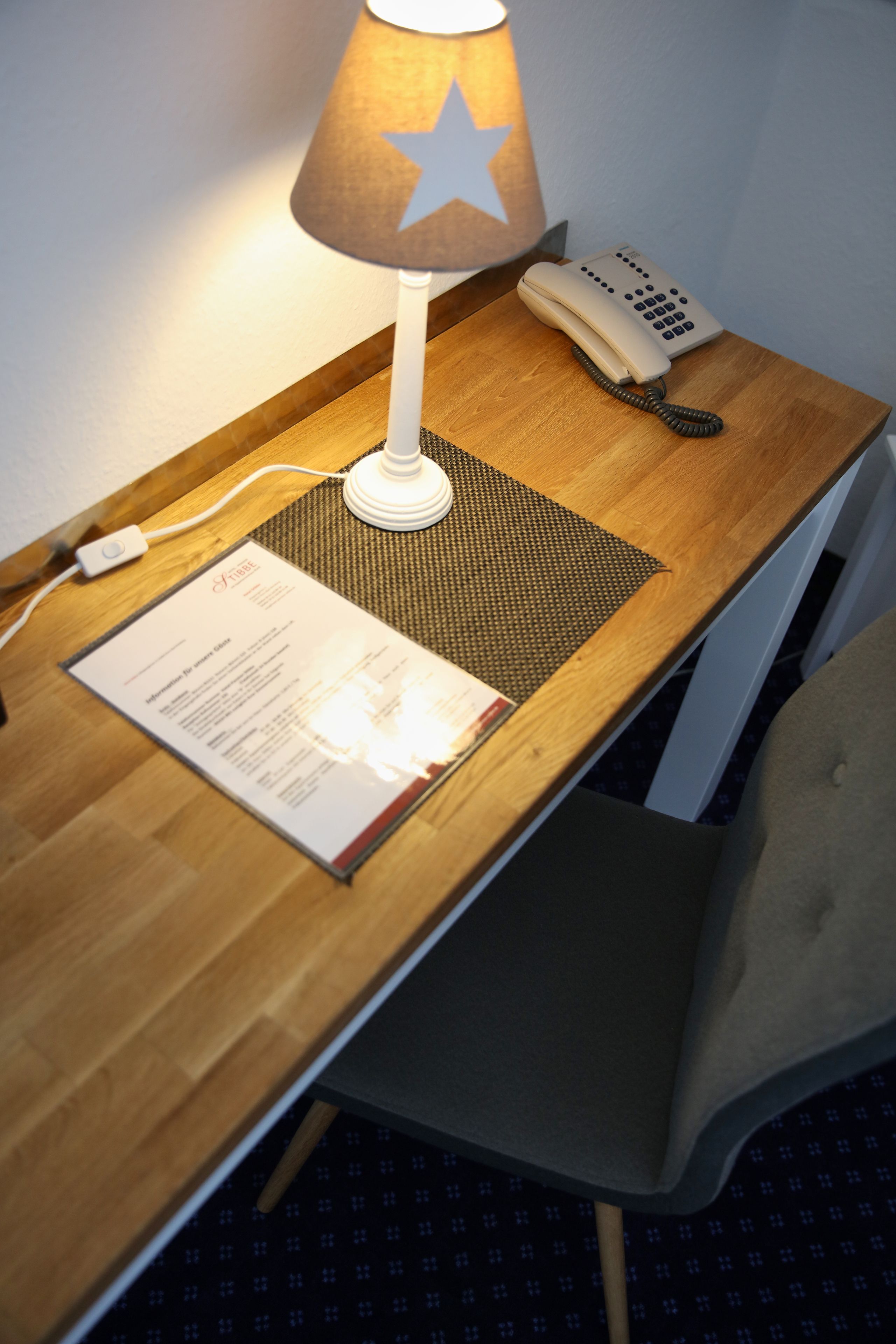 Un bureau en bois avec une lampe, un téléphone et un menu.