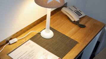 A wooden desk with a lamp, a telephone, and a menu.