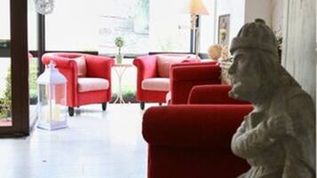 Una habitación con un sofá rojo, una estatua y una alfombra estampada.
