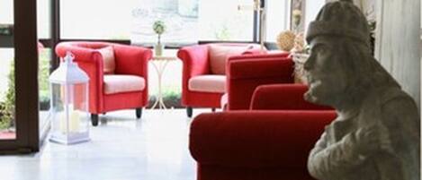 Una habitación con un sofá rojo, una estatua y una alfombra estampada.