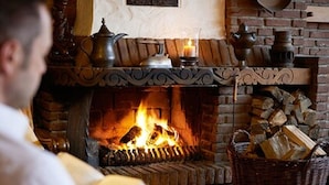 Una chimenea con leña, una vela y una tetera.
