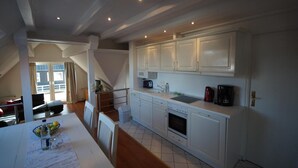 Une cuisine avec des meubles blancs, une cuisinière, un évier et une machine à café.