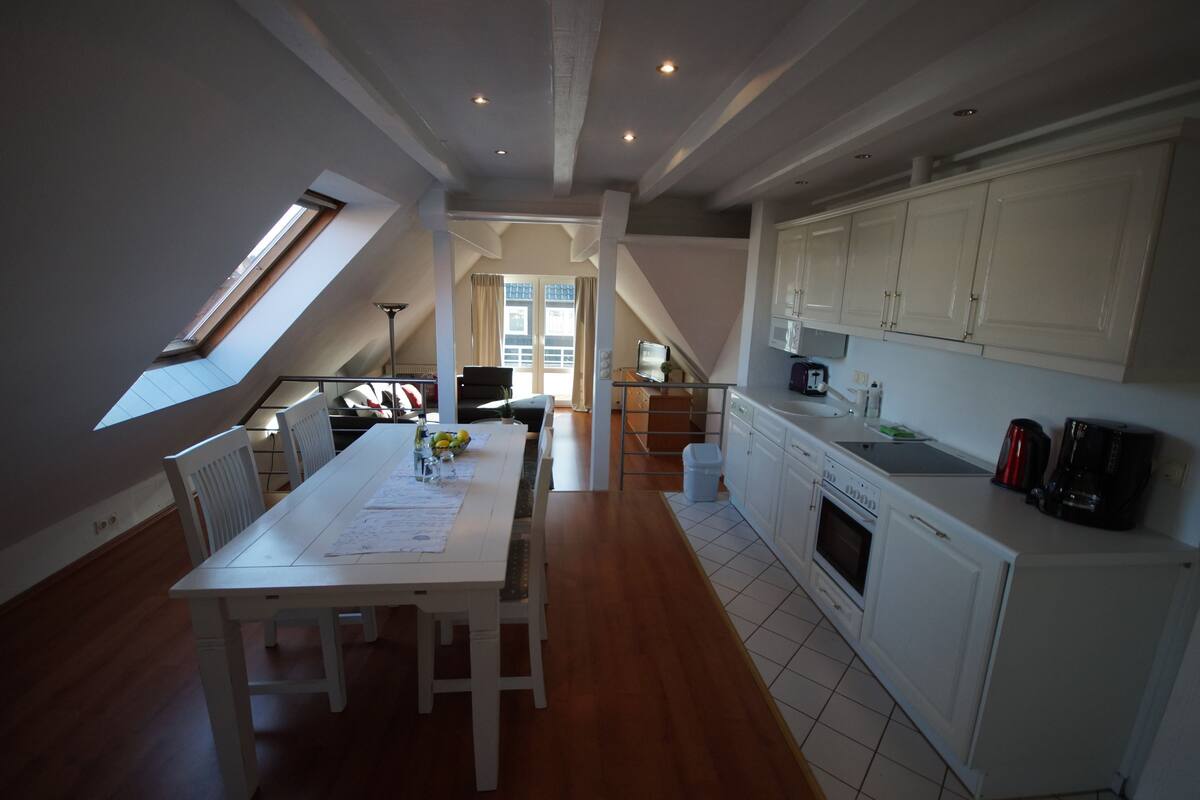 A spacious kitchen with white cabinets, a dining area with a table and chairs, and a visible skylight.