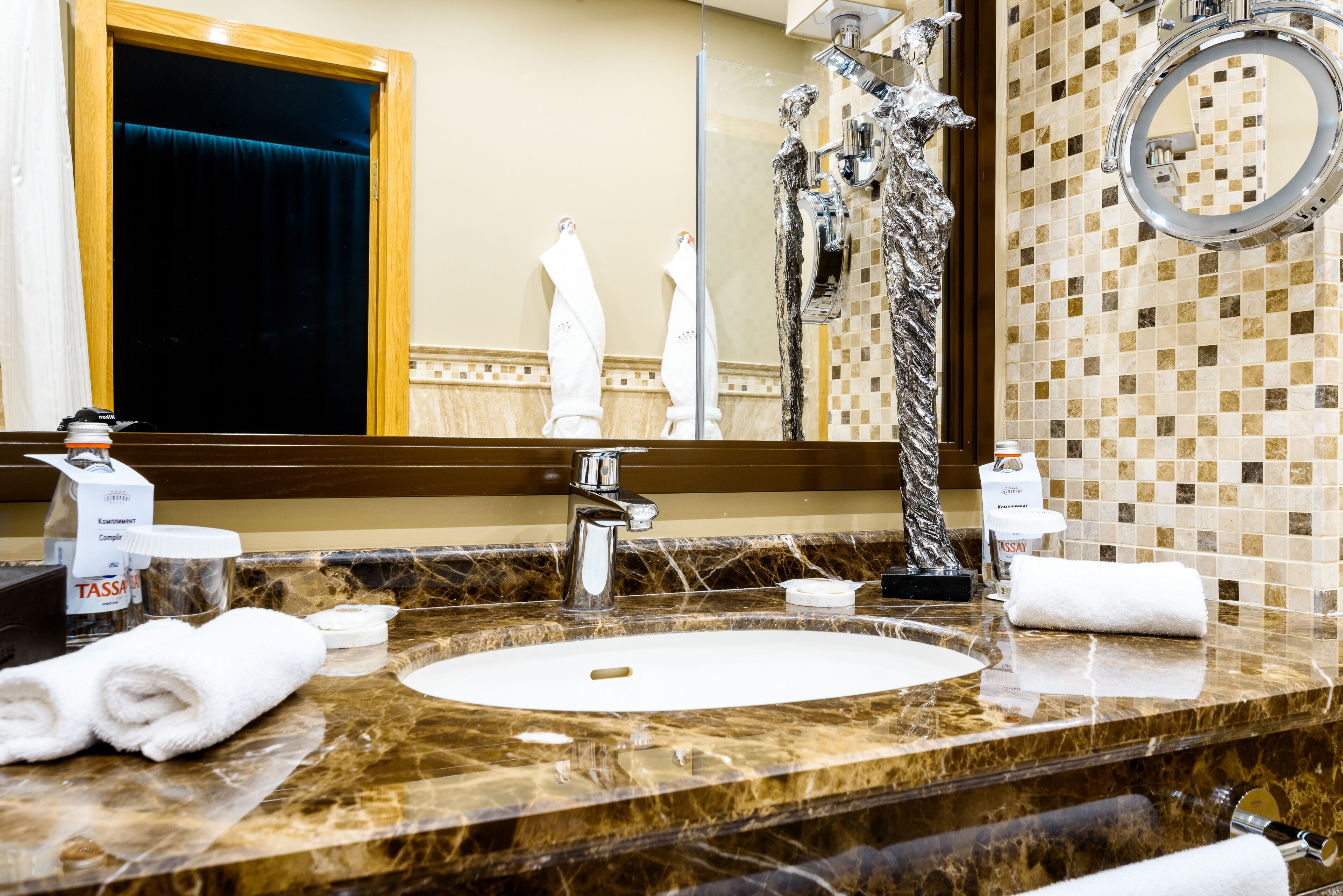A bathroom with a marble sink, a large mirror, and a shower with a decorative wall.