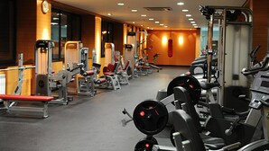 Ett gym med olika typer av träningsutrustning, inklusive styrketräningsmaskiner och konditionsmaskiner, uppställda i rader.