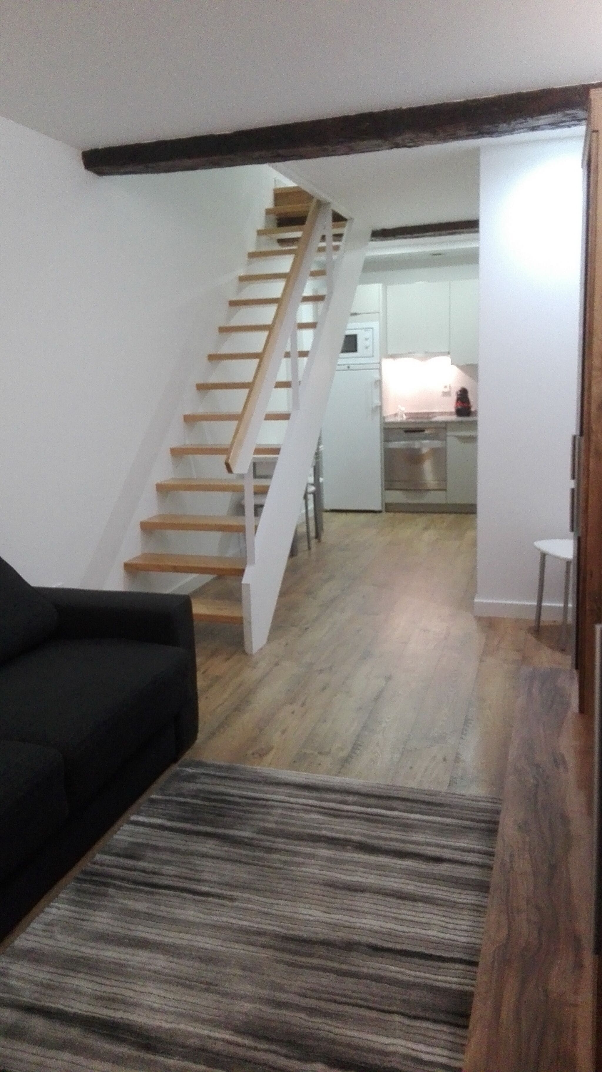 Una escalera que lleva a una cocina con microondas y lavabo.