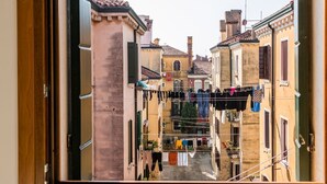 A narrow street with buildings on either side, featuring balconies with clothes hanging out to dry.
