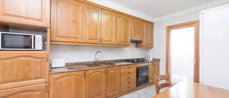A kitchen with wooden cabinets, a microwave, a toaster, a sink, and a stove.