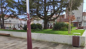 A public square with a marble statue, benches, and a trash bin. - Albergue Arraigos - Hostel (Melide)