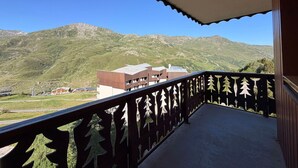 En balkon med udsigt til bjerge og en bygning i baggrunden.