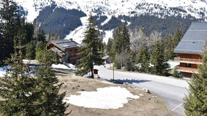 Un chalet au revêtement extérieur en bois, un télésiège et une vue imprenable sur les montagnes.