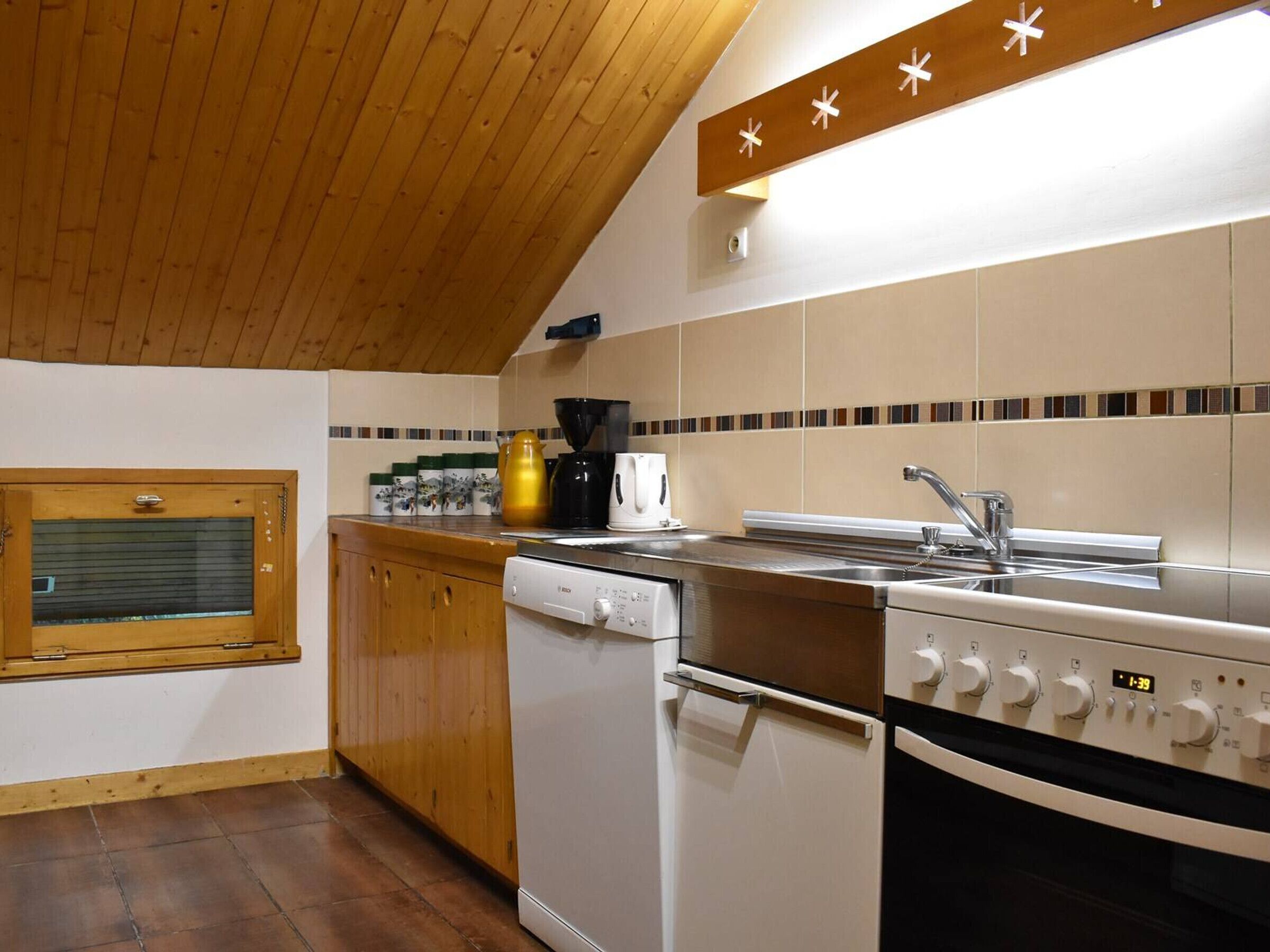 Una cucina compatta con mobili in legno, forno integrato, lavastoviglie e macchina da caffè.