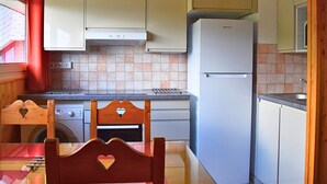 Una cocina compacta con lavadora incorporada, un refrigerador y armarios de madera.