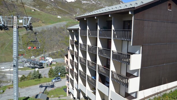 A multi-story building with balconies, a ski lift in the background, and a mountainous landscape. - Economical studio for 3 in the heart of Les Menuires (Les Menuires)
