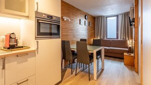 A modern kitchen with a built-in oven and a coffee machine, a dining area with a table and chairs, and a cozy seating area with a sofa and a window. - Renovated studio 4 pers, balcony, center Plagne Bellecôte (Plagne Bellecôte)