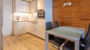 A compact kitchen with white cabinets, a built-in oven, and a dining area with a glass table and black chairs. - Renovated studio 4 pers, balcony, center Plagne Bellecôte (Plagne Bellecôte)