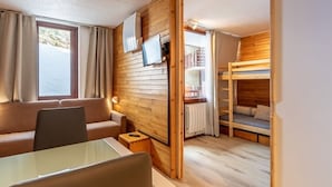 A cozy room with a wooden interior, a sofa, a table, a bunk bed, and a television. - Renovated studio 4 pers, balcony, center Plagne Bellecôte (Plagne Bellecôte)
