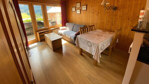 Ein gemütliches Zimmer mit Holzwänden und -decke, einer Couch, einem Tisch und einem Esstisch.