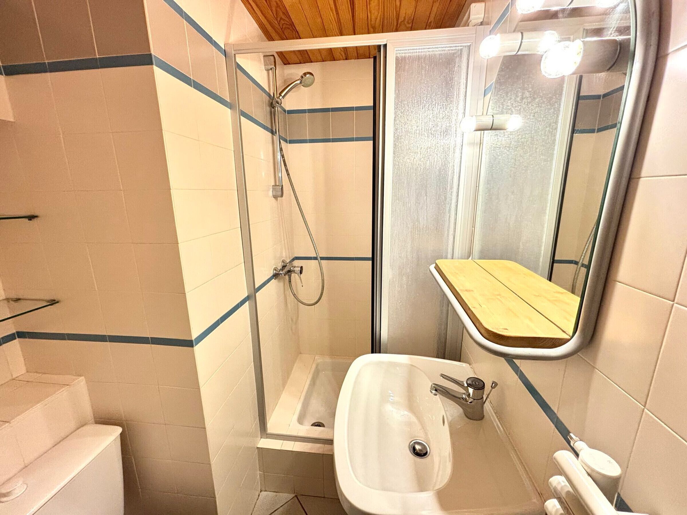 Une petite salle de bain comprenant une douche, un lavabo et un miroir.