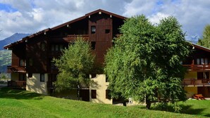 Un edificio de madera grande con varios balcones y montañas al fondo.
