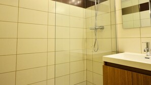 Un baño moderno con cabina de ducha de vidrio, tocador de madera y espejo sobre el lavabo.