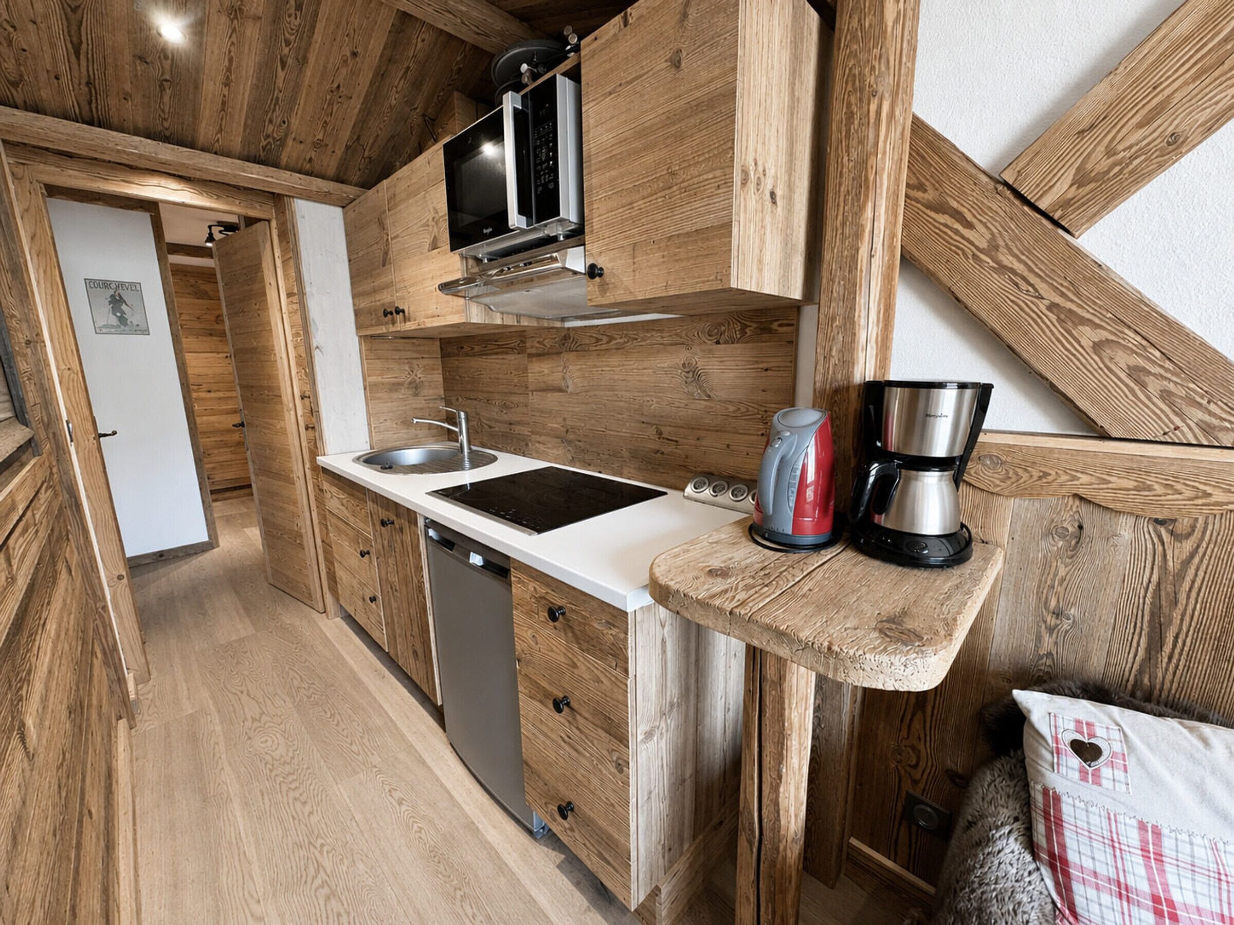 Eine kompakte Küche mit Holzschränken, einer eingebauten Mikrowelle, einem Spülbecken und einer Kaffeemaschine auf einer Holzausziehtafel.