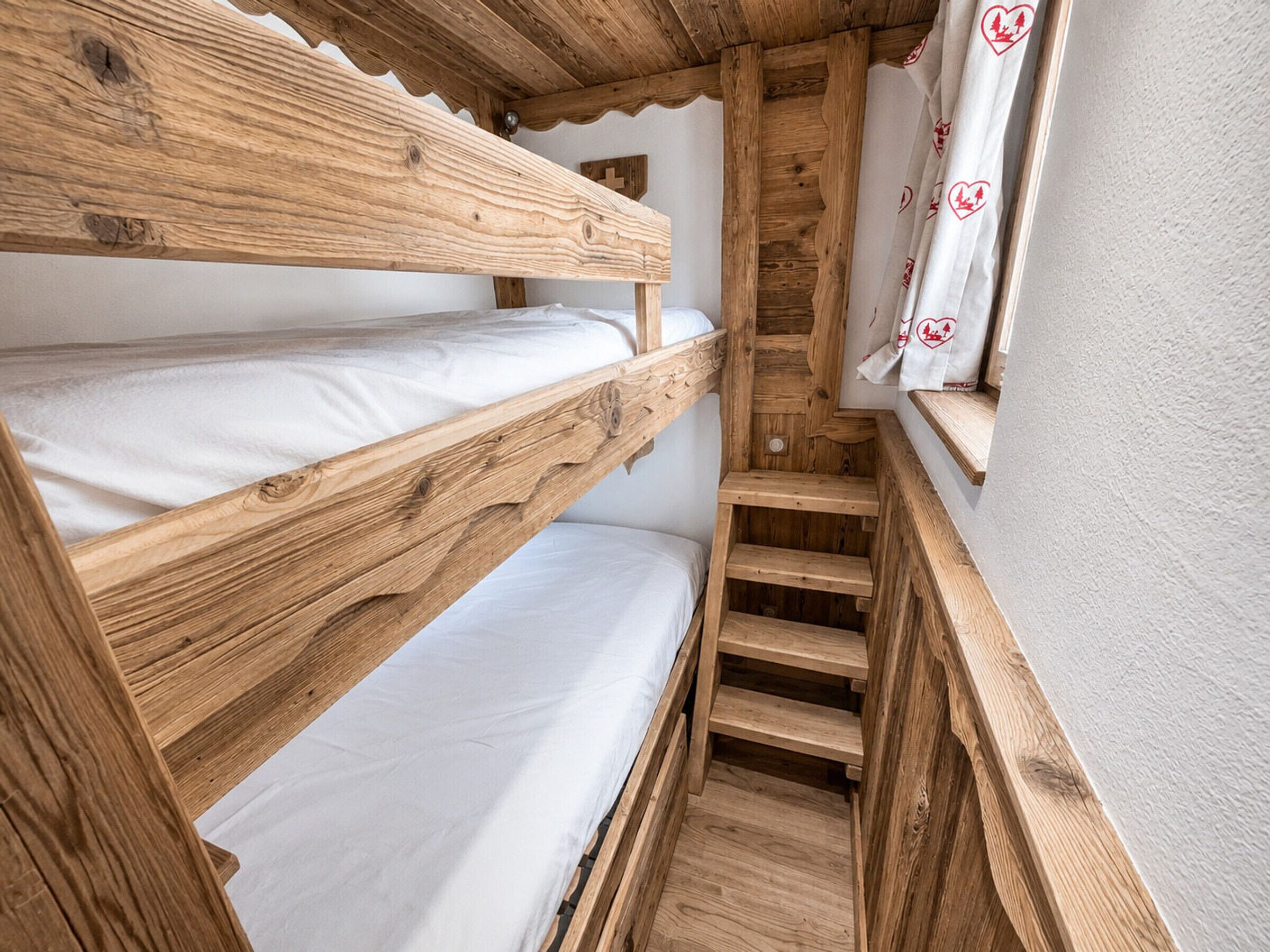 A wooden bunk bed room with a window and curtains.