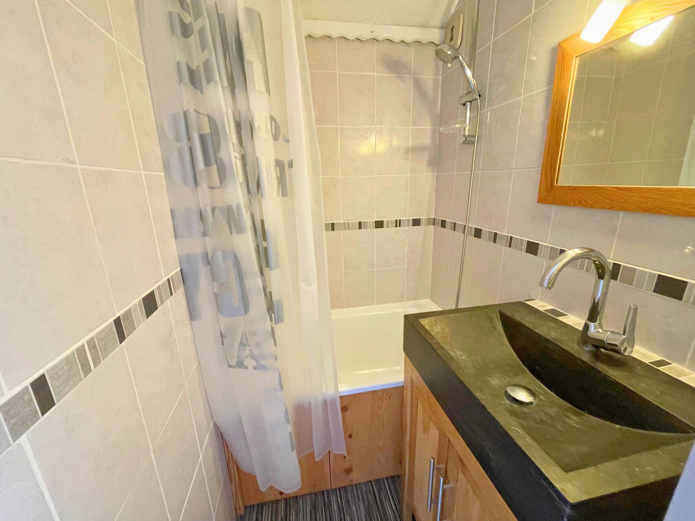Baño con ducha, lavamanos y espejo.