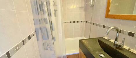 Baño con ducha, lavamanos y espejo.
