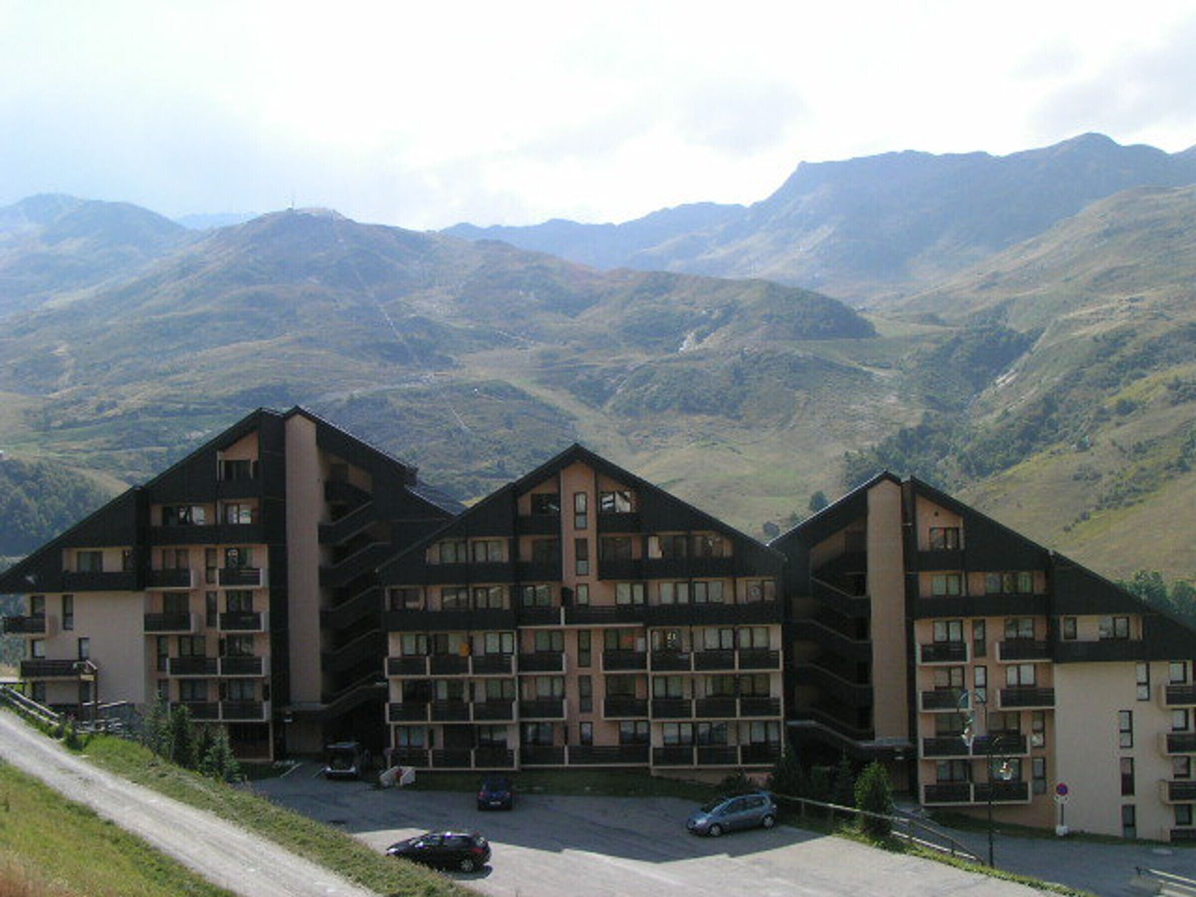 Un hôtel à plusieurs étages doté d’une architecture moderne, avec des balcons et un espace de stationnement à l’avant.