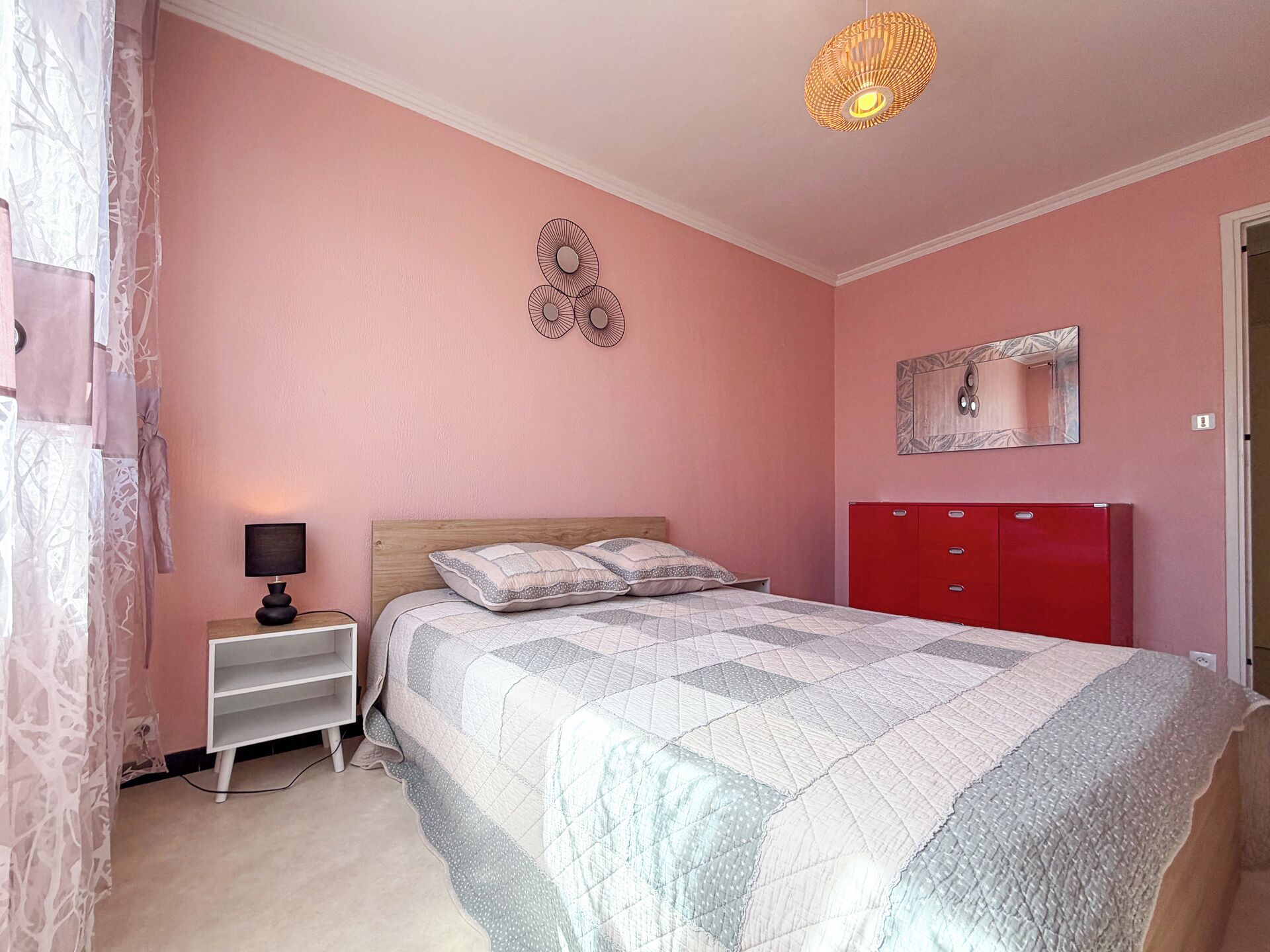 Un dormitorio con cama, mesita de noche, lámpara, cómoda y espejo.