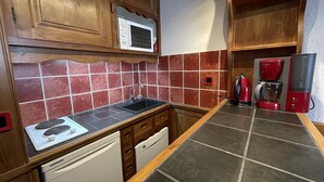 A compact kitchen with wooden cabinets, a microwave, a coffee maker, and a dishwasher.