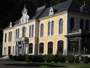 A historic building with a yellow facade, arched windows, and a balcony with a sign that reads "CINEMA". - Cauterets: 2 BR Apartment, 8 Guests, Wifi & Parking (Cauterets)