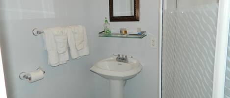 A bathroom with a white sink, a mirror, and two towels hanging on a rack.