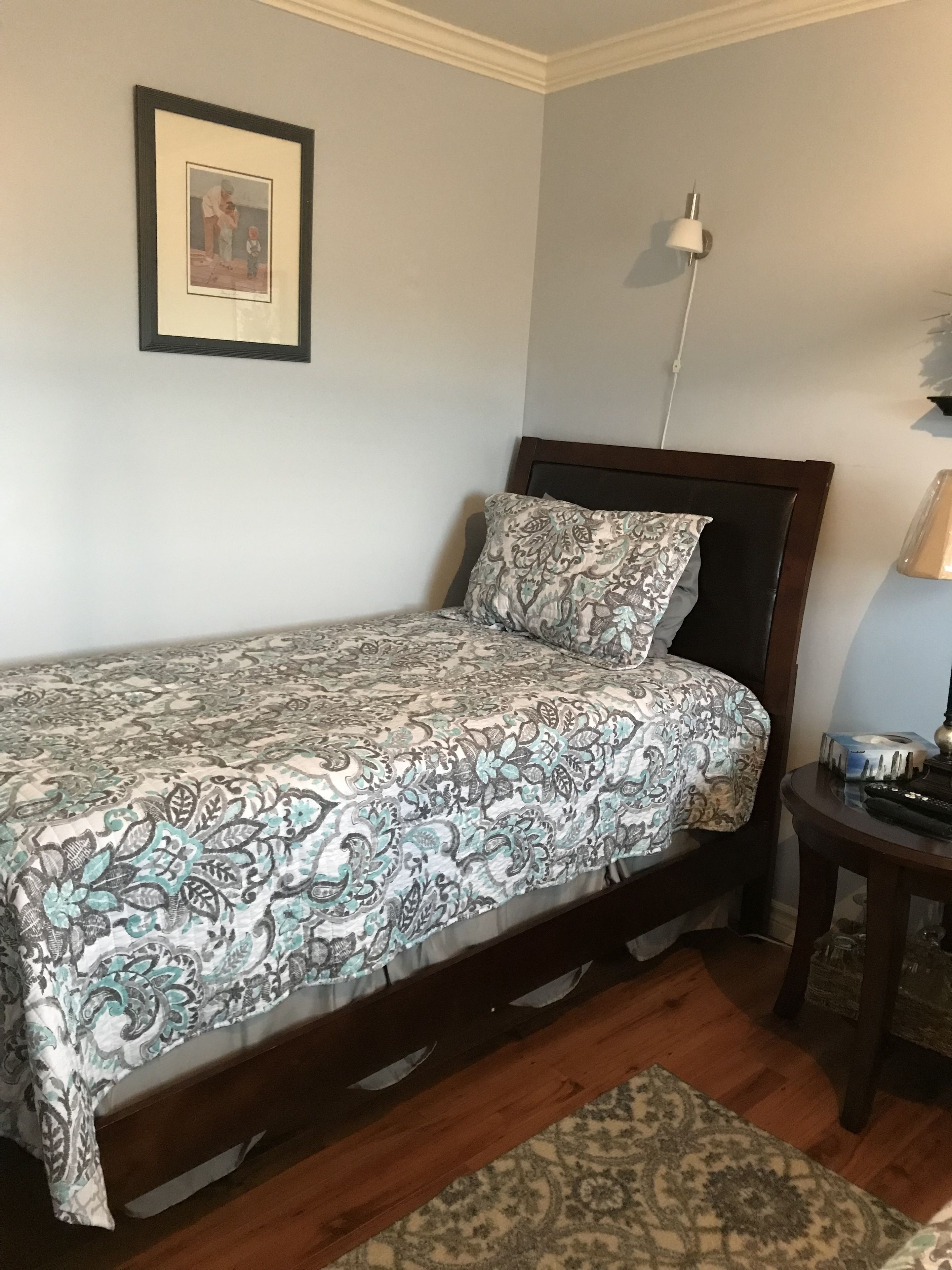 Un dormitorio con una cama, una mesita de noche, una lámpara y un cuadro en la pared.