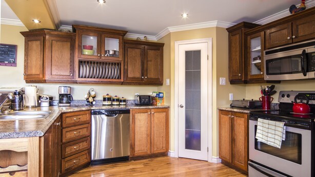 Una cocina con armarios de madera, electrodomésticos de acero inoxidable y encimera de granito.