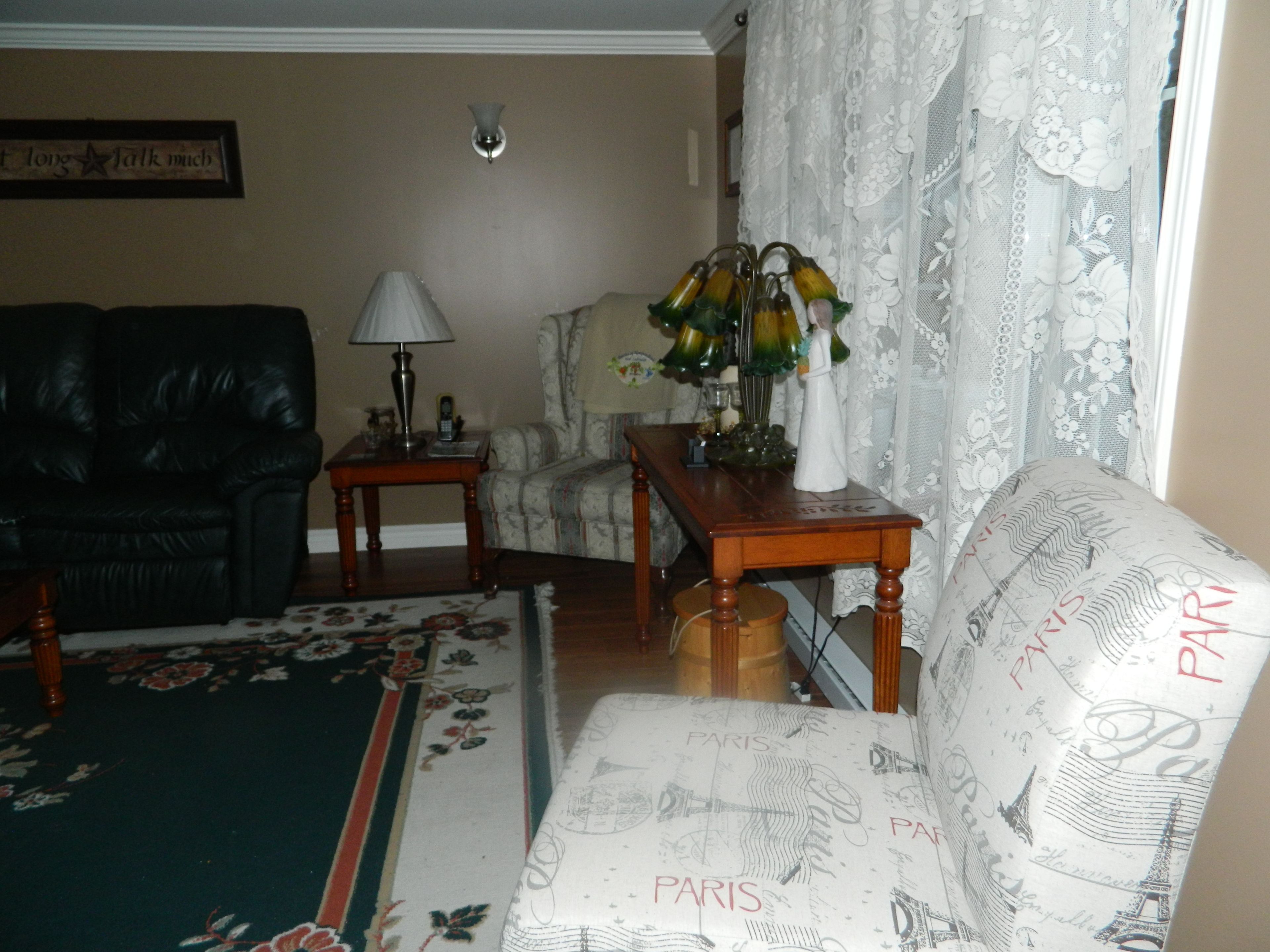 A living room with a sofa, a table, a lamp, and a chair.